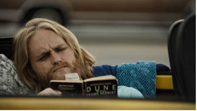 Dud reading Dune by Frank Herbert in his car - a newspaper clipping about his father's drowning is between the pages.