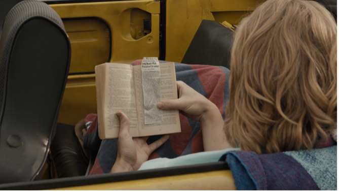 Another angle of Dud reading Dune by Frank Herbert in his car - a newspaper clipping about his father's drowning is between the pages.