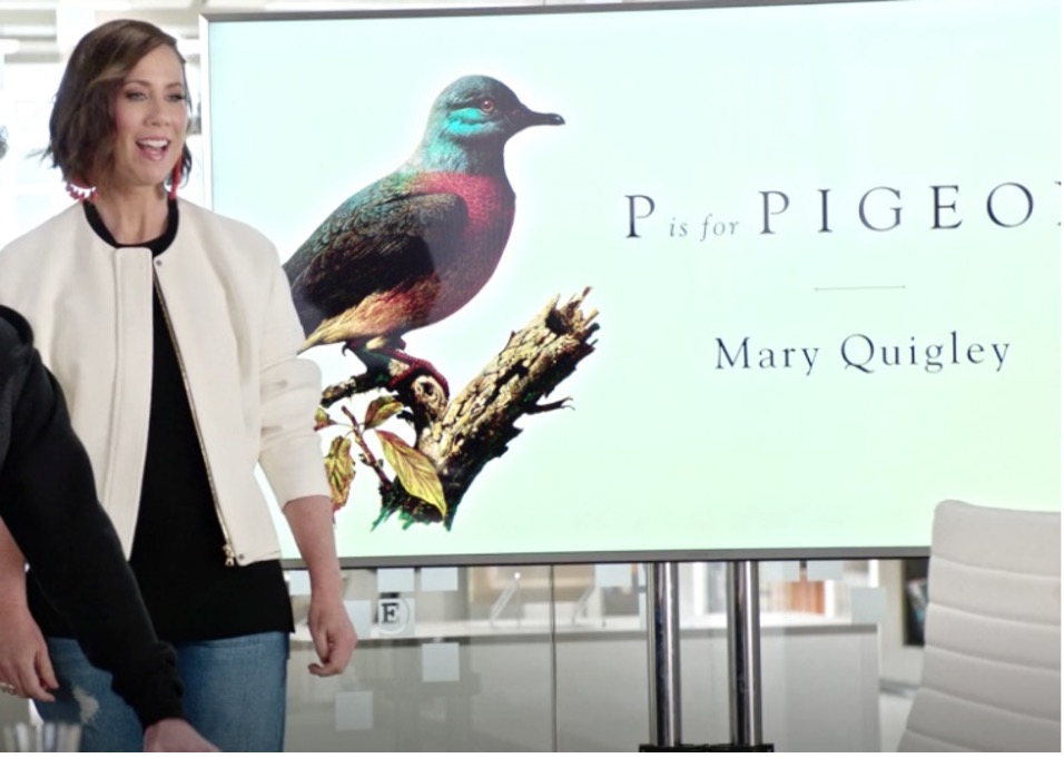 Diana, a marketing executive, brunette with a power bob, stands in front of a presentation. The first slide shows a multi-coloured bird on a branch and reads 