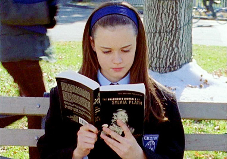 Rory, sitting on a bench, looking absorbed while reading Sylvia Plath.
