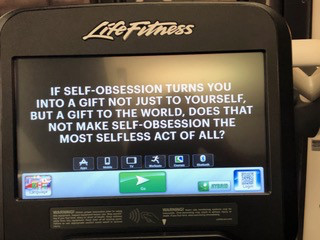 Photograph of the screen of a fitness machine, with text reading "If self-obsession turns you into a gift not just to yourself, but a gift to the world, does that not make self-obsession the most selfless act of all?