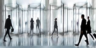 Image of several revolving doors with indistinct human figures passing through